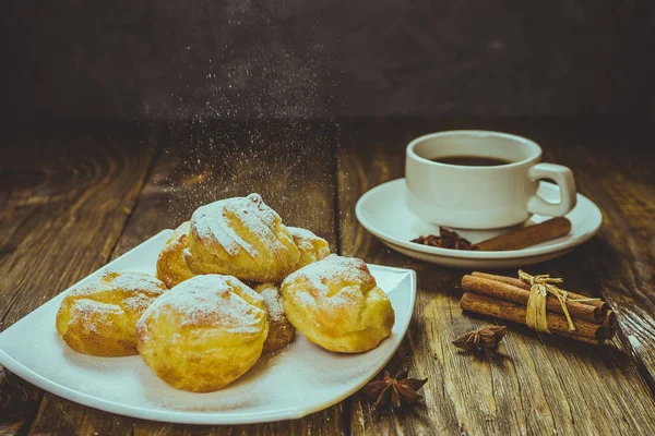 Lezzetli eklerleri şeker, krema ile serpilir üzerinde ahşap bir masa standı. Kopya spase.