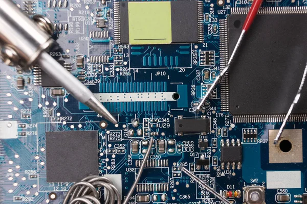 Tin the soldering iron and tweezers on the background of the motherboard. Macrophotography. — Stock Photo, Image