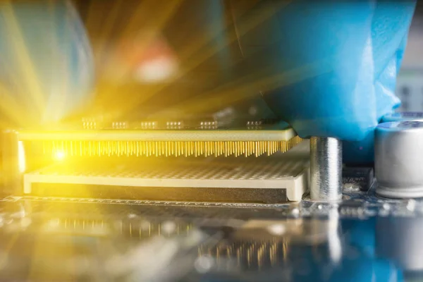 Una mano enguantada, colocando una CPU en la placa base. Macrofotografías . — Foto de Stock