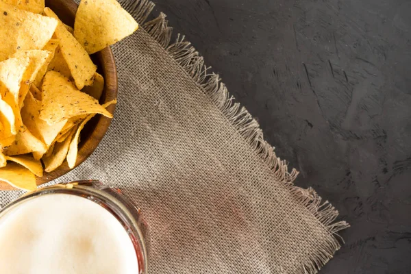 Cerveza negra, nachos y patatas fritas están sobre la mesa. Copiar espacio — Foto de Stock