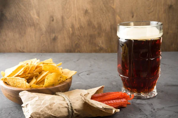 Cerveza negra, nachos y patatas fritas están sobre la mesa. Copiar espacio — Foto de Stock