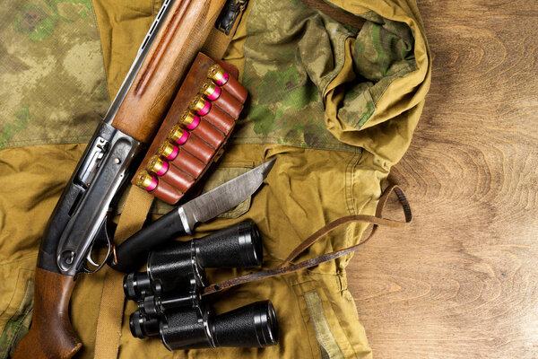 Охотничье ружье и боеприпасы лежат на деревянном фоне. Копирование пространства
