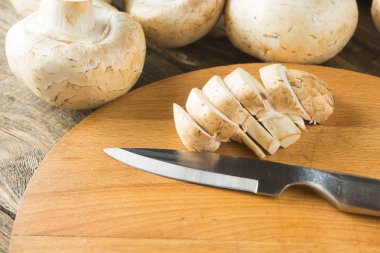 Champignon mantar ve ahşap kesme tahtası üzerinde bir bıçak.