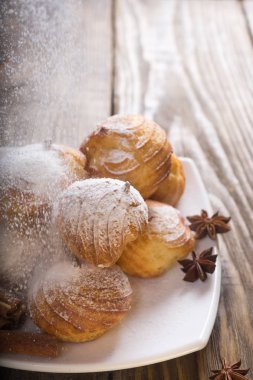 Lezzetli eklerleri şeker, krema ile serpilir üzerinde ahşap bir masa standı. Kopya spase.