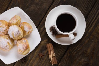 Lezzetli eklerleri şeker, krema ile serpilir üzerinde ahşap bir masa standı. Kopya spase.