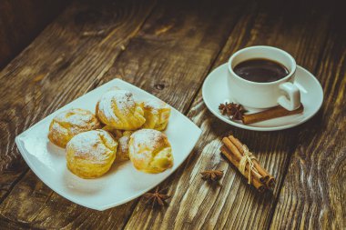Lezzetli eklerleri şeker, krema ile serpilir üzerinde ahşap bir masa standı. Kopya spase.
