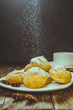 Lezzetli eklerleri şeker, krema ile serpilir üzerinde ahşap bir masa standı. Kopya spase.