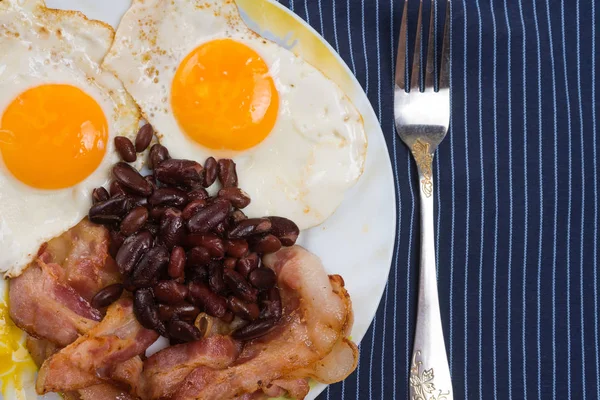 Prato com ovos mexidos, bacon e feijão em uma mesa rústica de madeira . — Fotografia de Stock