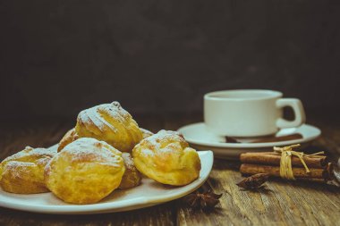 Lezzetli eklerleri şeker, krema ile serpilir üzerinde ahşap bir masa standı.
