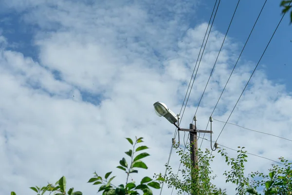 Stary drewniany słup elektryczny z lampą i wieloma kablami, które działają w różnych kierunkach, Chmura Niebo. — Zdjęcie stockowe