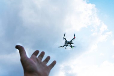 The man's hand reaches for the flying drone. Drone in focus.