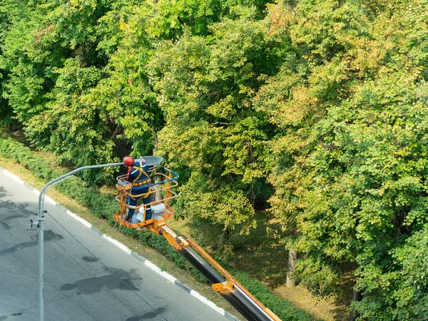 A szakember a lámpaoszlopokon lévő régi lámpák új ólomlámpákra való cseréjével foglalkozik.. — Stock Fotó