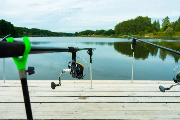 Pesca de carpas en el hermoso lago azul con cañas de carpa y vainas de caña en la mañana de verano. Pesca desde la plataforma de madera . —  Fotos de Stock