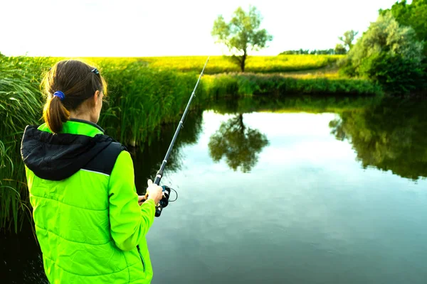 Das Mädchen fischt mit einer Spinnrute. Angeln im Sommer. — Stockfoto