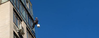 Endüstriyel tırmanış Yüksek binadaki camları silen bir tırmanıcı. Cam elementlerin temizlenmesi.