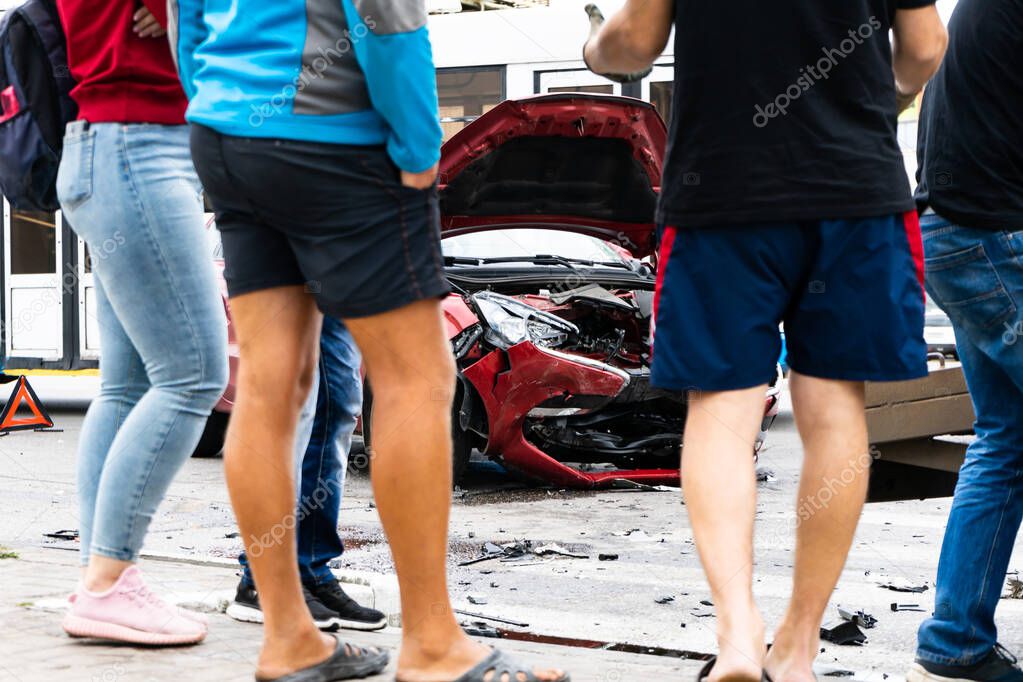 Pedestrians stand and look at the consequences of a car accident.