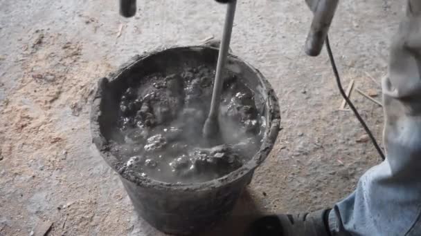 在一个黑色的小油罐中混合水泥用于建筑 工人在桶里搅拌石膏 工人在一个黑色的桶里搅拌解决方案 — 图库视频影像
