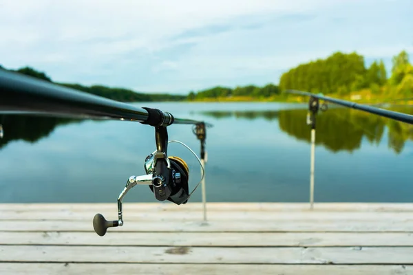 Rybaření kaprů na krásném modrém jezeře s kapry a pruty lusky v létě ráno. Rybaření z dřevěné plošiny. — Stock fotografie