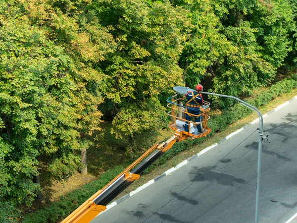 A szakember a lámpaoszlopokon lévő régi lámpák új ólomlámpákra való cseréjével foglalkozik.. — Stock Fotó