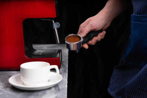 Un hombre con un portafilter en sus manos. El concepto de hacer café en una máquina de café. Foto en un tono bajo . — Foto de Stock