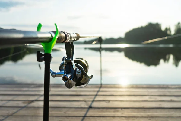 鯉ロッドと夏の朝にロッドポッドと美しい青い湖で鯉釣り。木造ホームからの釣り. — ストック写真