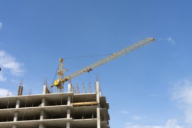 Mavi gökyüzüne karşı kule vinci olan inşaat alanı.