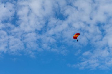 Paraşütçü mavi gökyüzüne paraşütle iniyor. Gökyüzünde paraşütçü. Gökyüzünde paraşüt altındaki insanlar.