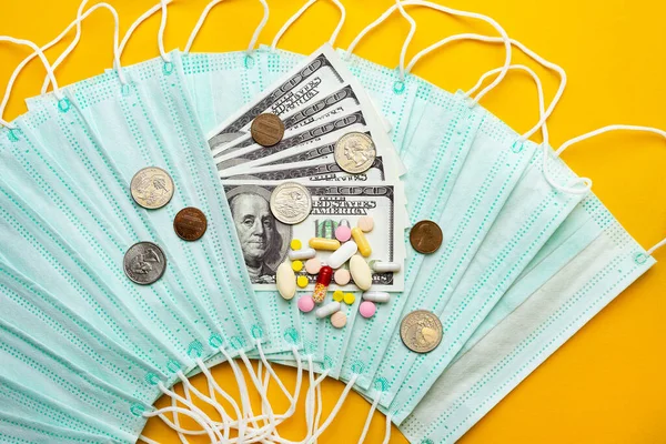 Sale of medical masks. Protective medical mask and different types of pills next to money on yellow background. Coronavirus concept. 2019 nCoV.