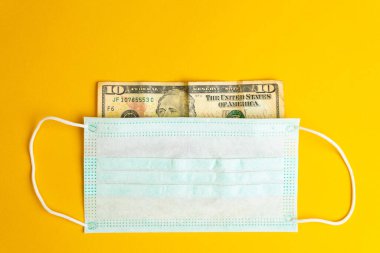 Sağlık maskesi banknotu kapatıyor. Kriz sırasında para birimi ve ekonomiyi koruma kavramları.