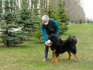 Bir adam yürüyüş sırasında köpeğine tıbbi maske takar..
