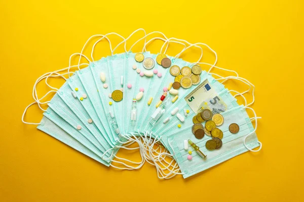 Sale of medical masks. Protective medical mask and different types of pills next to money on yellow background. Coronavirus concept. 2019 nCoV.