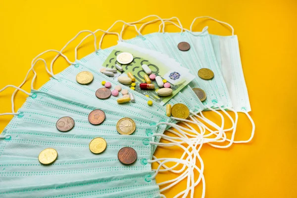 Sale of medical masks. Protective medical mask and different types of pills next to money on yellow background. Coronavirus concept. The concept of inflation in medicine