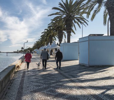Portekiz, Lagos 'taki gezinti alanı boyunca köpekleri gezdiren turistler