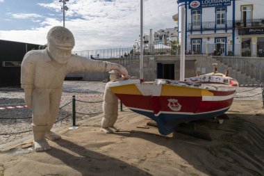 Albufeira, Algarve, Portekiz 'de tahta bir teknenin yanındaki taş heykeller.