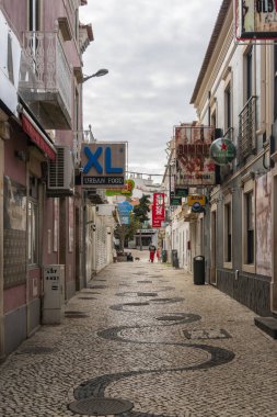 Albufeira, Algarve, Portekiz 'de dar bir sokakta desenli kaldırım taşları.