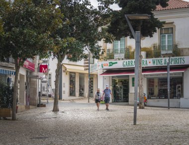 Orta yaşlı bir çift el ele tutuşup eski kasaba Albufeira, Algarve, Portekiz 'deki ana meydanda yürüyorlar.