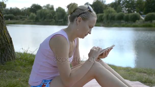 Jeune fille est assis sur la nature et travaille dans le smartphone .