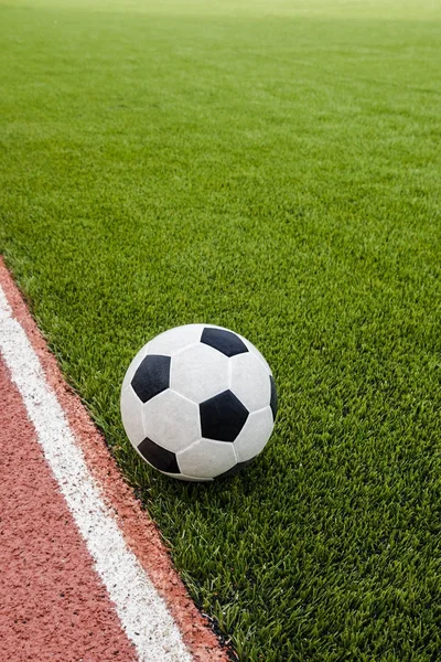 The football is on the artificial grass soccer field in the stadium.