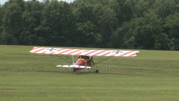 Avion cu dungi roșii taxând pe teren de iarbă — Videoclip de stoc