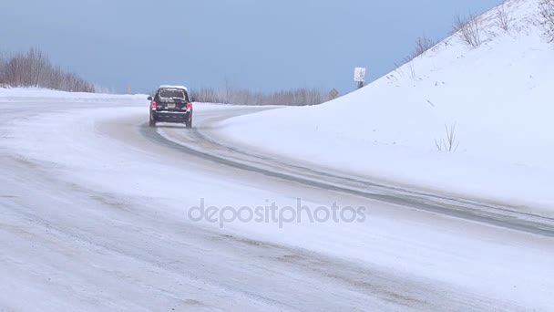 Tráfico de invierno va alrededor de curva helada en carretera montañosa nevada Video de stock libre de derechos