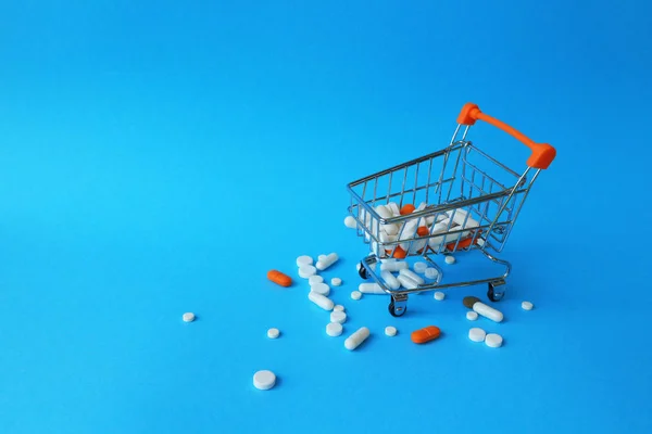 Tablet, kapsül ve mavi bir arka plan üzerinde bir alışveriş sepeti. İlaçlar, tedavi için fiyatları alış kavramı. Eczane satış.