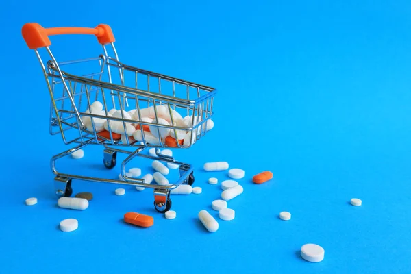 Tablet, kapsül ve mavi bir arka plan üzerinde bir alışveriş sepeti. İlaçlar, tedavi için fiyatları alış kavramı. Eczane satış.
