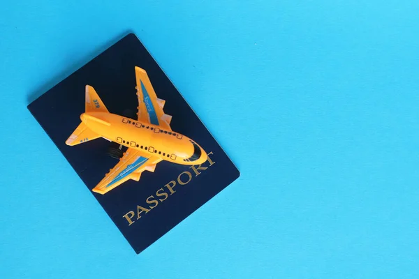 Mavi arka planda pasaport ve uçak oyuncağı