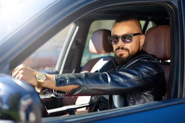Fiducioso uomo barbuto elegante in occhiali da sole alla guida di una macchina — Foto Stock