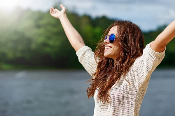 Hermosa modelo femenina sonriente disfrutando de la libertad con las manos levantadas —  Fotos de Stock