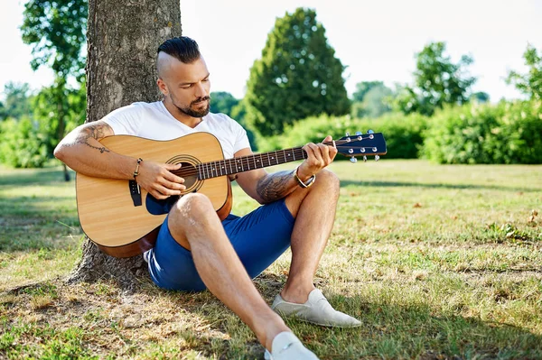 Bonito homem dobrando guitarra ao ar livre — Fotografia de Stock