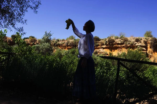 Gölgede, türbanlı, üzümlü bir kadın. Valle dei Templi, Giardino della Kolymbetra, Agrigento, Sicilya, İtalya