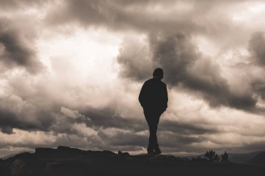 Çocuk siluet arka planda bulutlar ve karanlık. Yalnızlık, özgürlük, umutsuzluk ya da çaresizlik duygusu. Canlı ve güçlü vinyet etkisi.