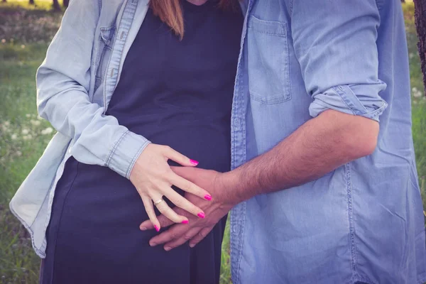 Cropped shot view of expecting parents hugging and holding hands around pregnant belly. Pregnancy, maternity and new family concept. — Stock Photo, Image