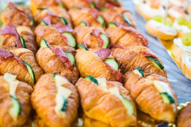 Mini kruvasan mezeleri, peynir ve salamlı ziyafet masasında. Doğum günü partisi için atıştırmalıklar..